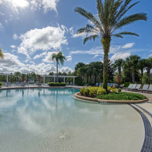Resort-style pool at Watersong Resort in Davenport Florida with palm trees and lounge chairs