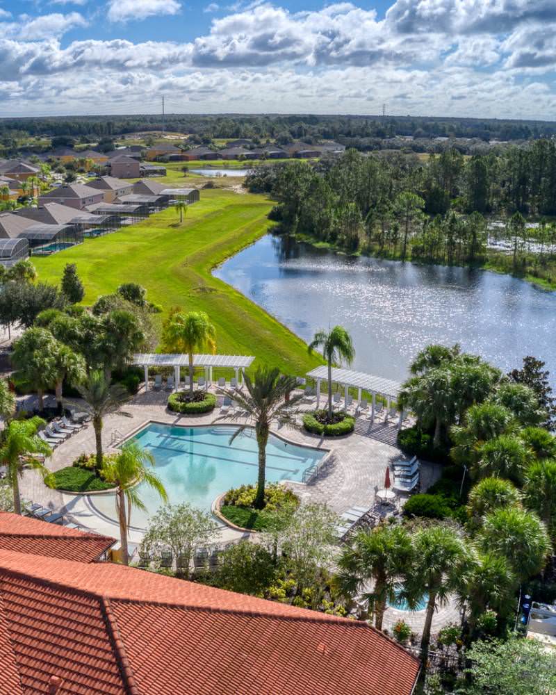 Aerial view of Watersong Resort in Davenport Florida featuring pool, palm trees, and lakefront homes